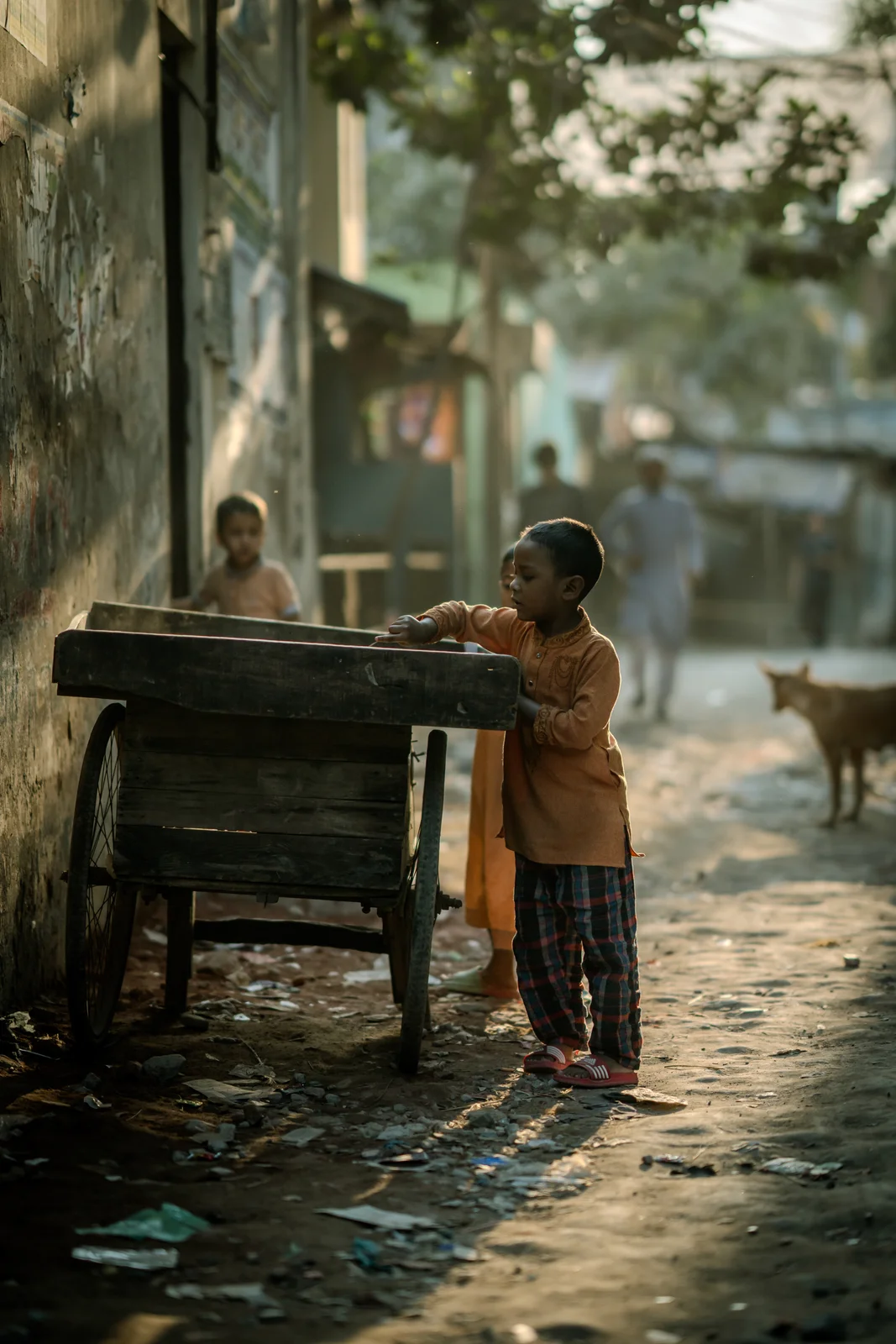 Kind an einem Holzkarren in einer Gasse · Bangladesch
