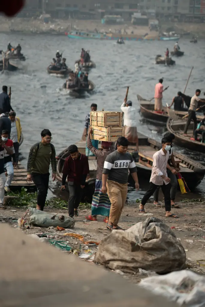 Menschen und Boote an einem geschäftigen Flussufer · Bangladesch