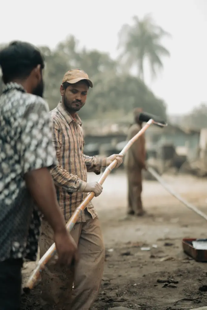 Männer streichen eine lange Stange · Bangladesch